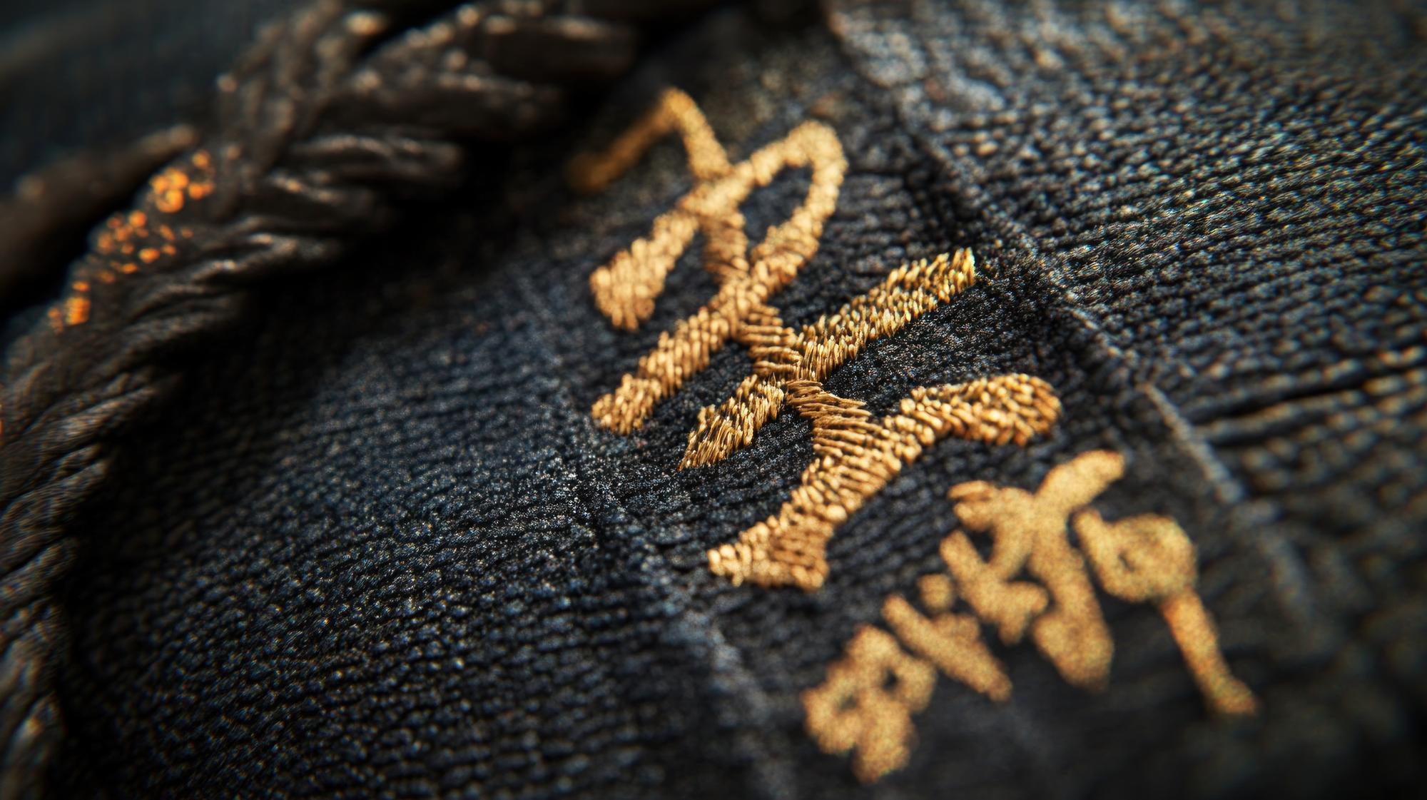 close-up of gold thread embroidery on dark fabric